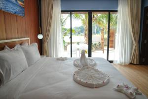 um quarto com uma cama branca com sapatos em One Beach Private Villa em Phumĭ Kaôh Rŭng Sâmlœ̆m Khnŏng