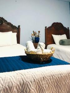 1 dormitorio con 2 camas y una cesta en la cama en Casa de los Abuelos Hotel, en Tecpán Guatemala