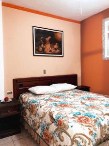 1 dormitorio con 1 cama y una pintura en la pared en Casa de los Abuelos Hotel, en Tecpán Guatemala