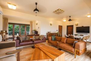 uma grande sala de estar com sofás e uma televisão em Pawna By Hangout Villas em Lonavala