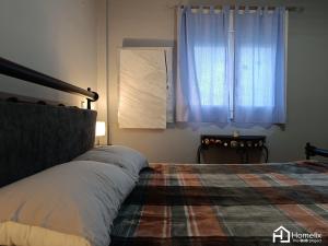 sypialnia z łóżkiem z kocem i oknem w obiekcie Άνετο και ήσυχο διαμέρισμα με θέα w Chalkidzie