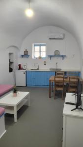 a large kitchen with blue cabinets and a table at Kamaraki Aroniadika in Kythira