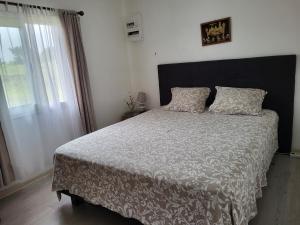 um quarto com uma cama com um edredão branco e uma janela em Case Créole Soalaze em Salazie