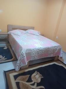 1 dormitorio con 1 cama con colcha rosa y blanca en Kipseli 1, en Kozani