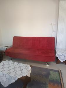 Kipseli 1 في كوزاني: أريكة حمراء في غرفة معيشة مع طاولة