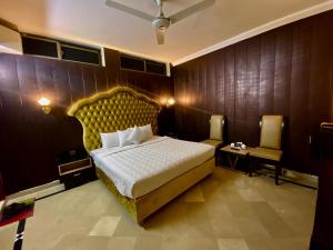 a bedroom with a large bed with a gold headboard at Orbit Residency F-7 in Islamabad