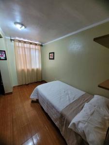 een slaapkamer met een bed en een houten vloer bij Departamento a 2 cuadras de plaza in Ayacucho