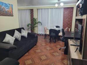 een woonkamer met een zwarte bank en een tafel bij Departamento a 2 cuadras de plaza in Ayacucho