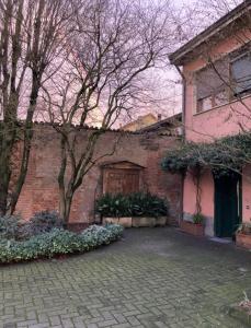un edificio de ladrillo con una puerta y un árbol en Il cortiletto en Quartiano