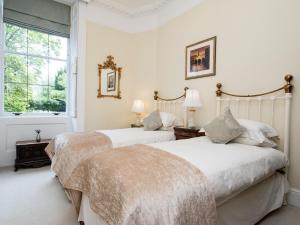 Duas camas num quarto branco com uma janela em Royal Crescent Apartment em Bath