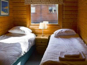 two beds in a wooden room with a window at Red Kite Lodge in Legbourne