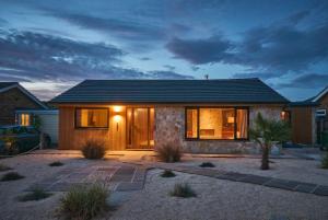 a home with a lit up front door at dusk at Cromer Luxury Palm Springs Bungalow with Pool Room in Overstrand