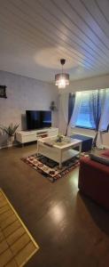 a living room with a couch and a tv at 3 bedrooms, sauna and kitchen All house in Pori