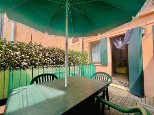 a green table with two chairs and an umbrella at Appartamento con terrazza centrale ed accogliente in Venice