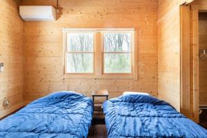 twee bedden in een kamer met een raam bij コテージLog in Nasu