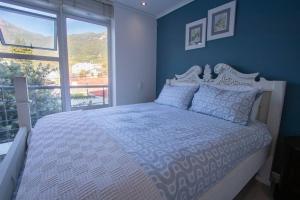 Cet appartement comprend une chambre dotée d'un lit avec un mur bleu et une fenêtre. dans l'établissement Victoria Views, au Cap