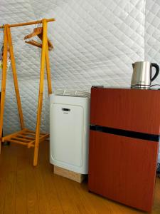 a small white refrigerator in a room with a bed at G-4 Gramping Sauna 白馬森のわさび農園 in Hakuba