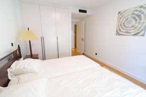 Un dormitorio con una gran cama blanca y una lámpara en Saint Lucas Suíte, en Funchal