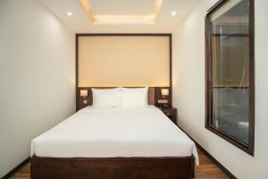 a bedroom with a large white bed with a window at Palazzo Boutique Hotel in Danang