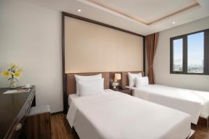 a hotel room with two beds and a large window at Palazzo Boutique Hotel in Danang
