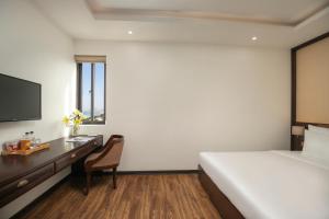 a bedroom with a bed and a desk with a computer at Palazzo Boutique Hotel in Danang