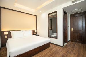 a bedroom with a white bed and a wooden floor at Palazzo Boutique Hotel in Danang