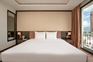 a bedroom with a large white bed and a window at Palazzo Boutique Hotel in Danang