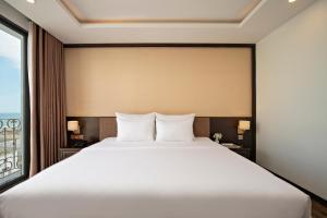 a bedroom with a large white bed and a window at Palazzo Boutique Hotel in Danang