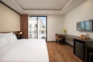 a hotel room with a bed and a desk and a television at Palazzo Boutique Hotel in Danang