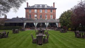 un gran edificio con mesas y sillas en el césped en The Riverside House Hotel en Mildenhall