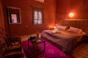 a bedroom with a bed and a table and a mirror at Hotel Kasbah Sahara in Mhamid