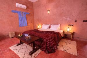 Hotel Kasbah Sahara في امحاميد: غرفة نوم بسرير كبير وطاولة
