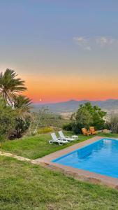 - une piscine avec 2 chaises longues et un coucher de soleil dans l'établissement Dar Bakkali Nadi, à Tanger