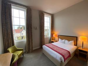 a hotel room with a bed and two windows at The Riverside House Hotel in Mildenhall