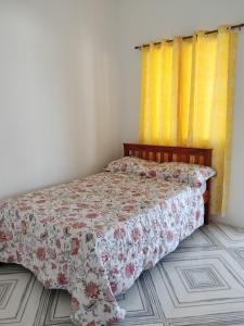 a bedroom with a bed with a floral bedspread at GmL Lodge House in Daanbantayan