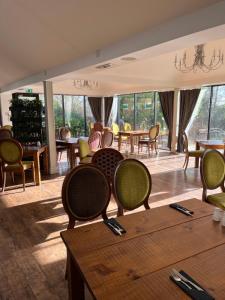 uma sala de jantar com cadeiras, mesas e janelas em The Riverside House Hotel em Mildenhall