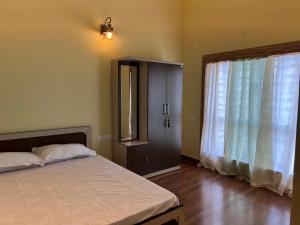 a bedroom with a bed and a large window at Sreemati - A Tranquil Villa in Shānti Niketan