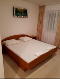 1 dormitorio con 1 cama con sábanas blancas y ventana en Apartments Villa Glavinić, en Neum