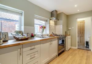 a kitchen with white cabinets and a counter top at Seascape Cottage in Reydon