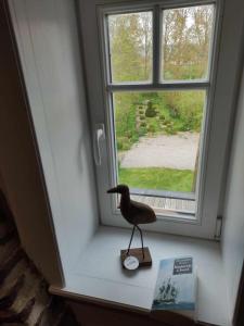 a bird statue sitting on a window sill next to a book at Manoir du Kasteelveld in Cassel