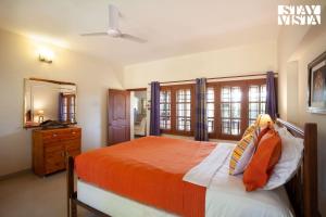 ein Schlafzimmer mit einem Bett mit einer orangefarbenen Decke in der Unterkunft StayVista at Mikkie House 3 Bedroom Villa in Aivarkhandpur