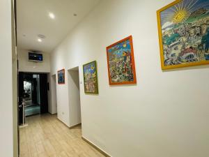 a hallway with paintings on a white wall at Hostel Mancini Naples in Naples