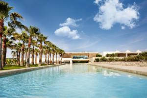 a swimming pool with palm trees in front of a building at Two Rooms Hotel in Yağcılar