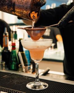 a person pouring a drink into a martini glass at Relais Corte Degli Aragonesi in Ischia