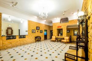 Habitación con pared de piedra, mesa y sillas. en Hotel Rawalkot Jaisalmer en Jaisalmer