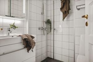 ein Bad mit einer Dusche und weißen Fliesen in der Unterkunft Lovely townhouse apartment close to the city centre in Bergen