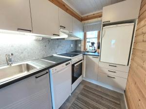 a small kitchen with white cabinets and a sink at Holiday Home Honkakoli 1 in Kolinkylä