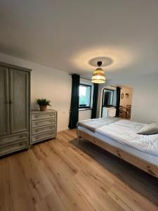 a bedroom with a large bed and a dresser at Apartament Jeziorna in Ocypel