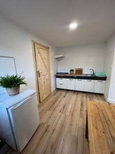 cocina con armarios blancos y suelo de madera en Apartament Jeziorna en Ocypel