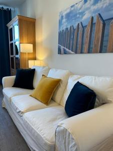 un sofá blanco con almohadas en la sala de estar en Ferienwohnung Landhaus 44 Citynah, toskanischer Flair, en Hamburgo